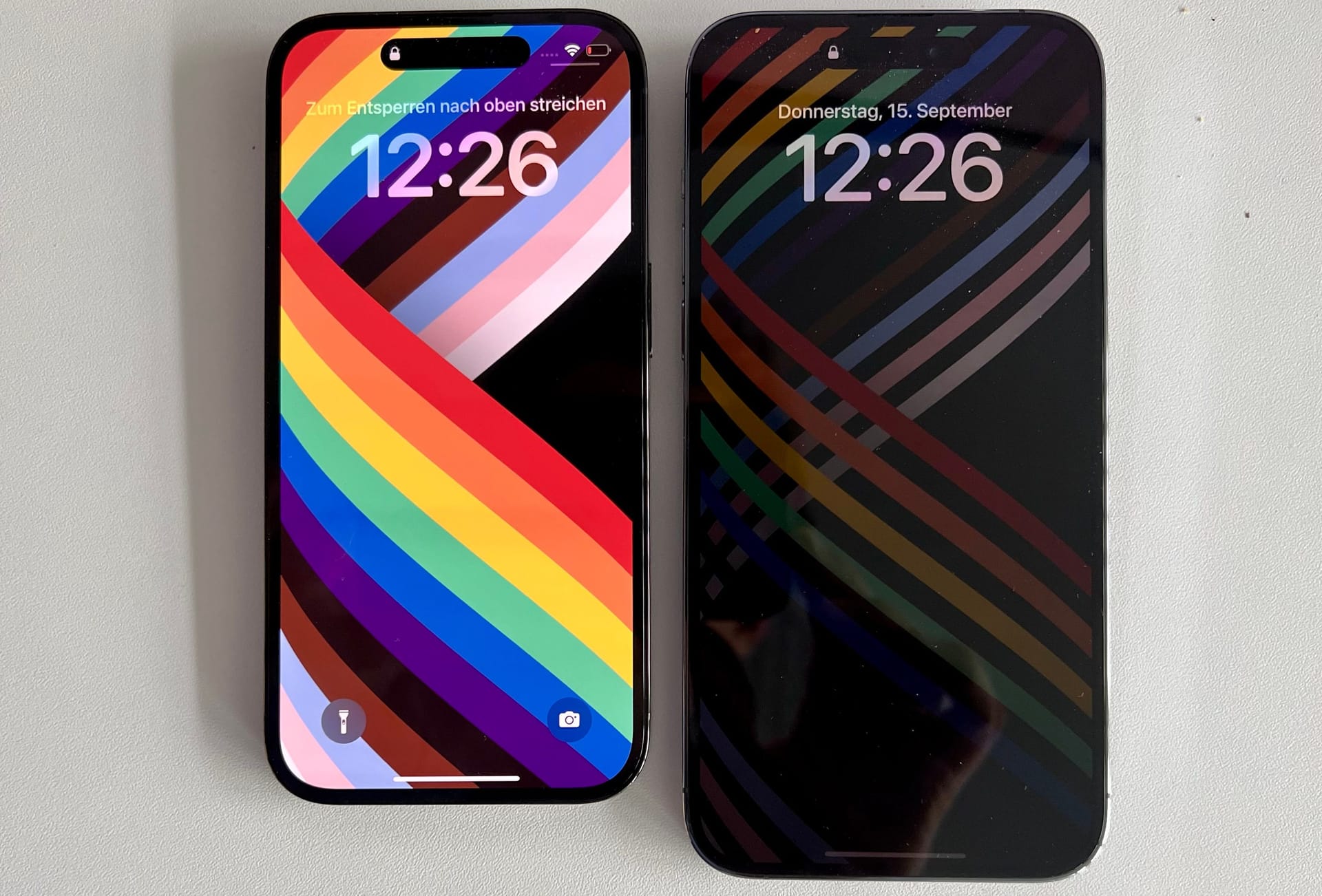 iPhone 14 Pro (links) mit aktivem Sperrbildschirm und iPhone 14 Pro Max mit Bildschirm im Always-on-Modus.